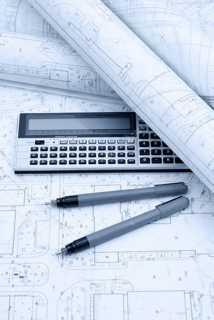Architectural plans, calculator and drawing utensils. Picture in blue tone.