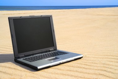 Modern dizüstü kum üzerinde yalan. Plaj ve arka planda temiz mavi gökyüzü.