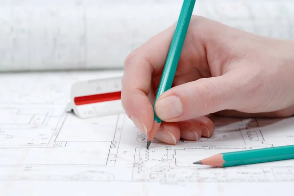 Woman\'s hand holding pencil and architectural plans