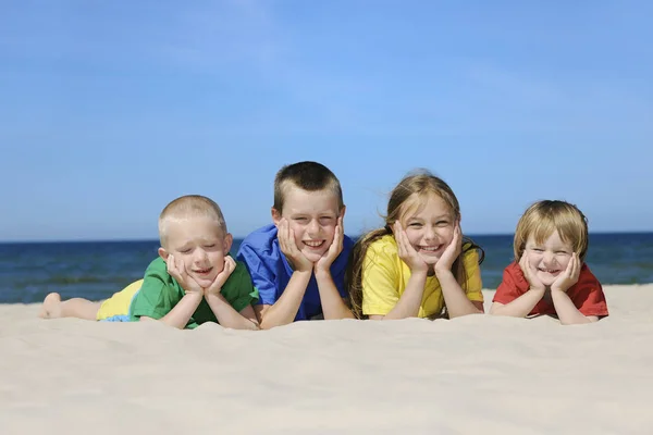 两个女孩和两个男孩穿着五颜六色的 t恤躺在沙滩上 — 图库照片
