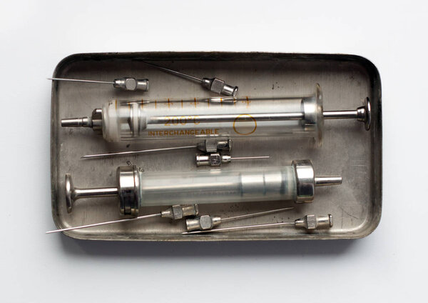 An old glass syringes and a metal box-sterilizer.