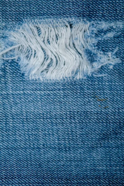 Blue Jean Textur mit einem Loch und Fäden. — Stockfoto