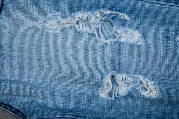 Blue Jean Textur mit einem Loch und Fäden. — Stockfoto