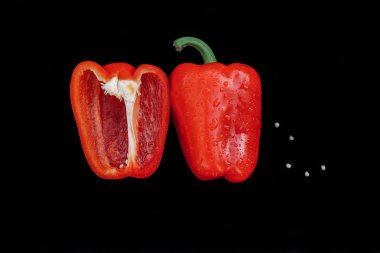 Siyah mutfak masa üstü görünümünde yeşil peduncle ve dağınık tohumlar ile yarım tatlı, kırmızı biber kesilmiş iki yarısı