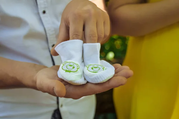 Anne anne ve baba, bir adam ve bir kadın yakın ayakta, baba elinde beyaz booties yenidoğan yakın çekim tutar