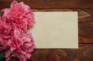 Kahverengi ahşap arka planda pembe şakayık buketi. Mesaj, konsept kapağı ve selamlama için eski bir kart.