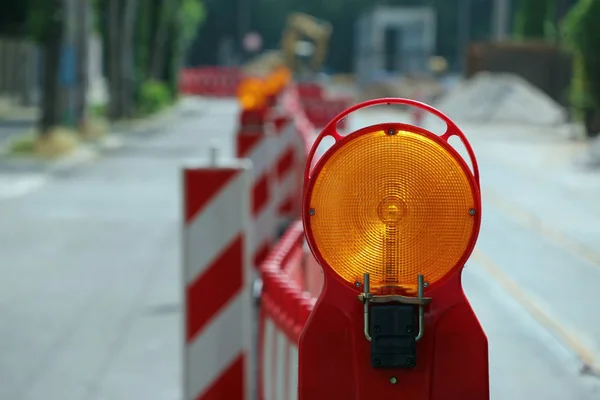 road under construction with signal lamps and construction fence