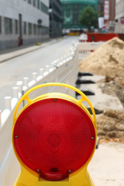 road under construction with signal lamps and construction fence