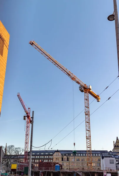 Construction site of a modern office, bank and commercial building with equipment and supports and zei cranes against blue sky