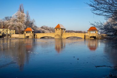 Ağaçlar ve mavi gökyüzü, weir ile kısmen donmuş nehir 