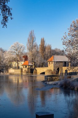 Ağaçlar ve mavi gökyüzü, weir ile kısmen donmuş nehir 