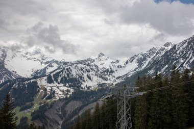 Avusturya Alpleri'nde kar ile ilkbaharda yüksek dağlar, yeşil çayırlar ve ağaçlar ile bir alp manzara Panorama