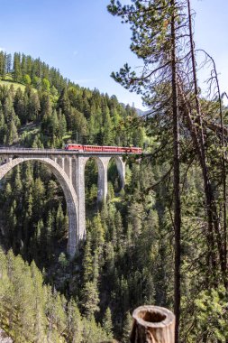 Davos-Wiesen, Switzerland-June 07,2019 View from the historic Wiesener Viaduct with a train of the Rhaetian Railway near the town Davos Wiesen, Swiss Alps clipart