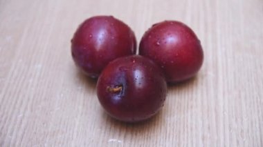 Ahşap masa üzerinde üç Erik üzerinde düşen su