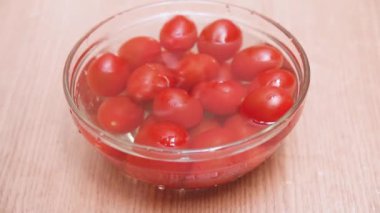 Ahşap bir masaya su ve diğer kiraz domates ile bir kase içine düşme domates