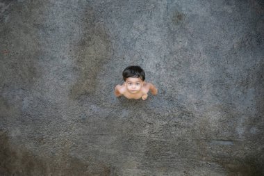 Şirin bebek çocuk yürümeye başlayan çocuk - ıslak bir gri yerde çıplak - üstten görünüm