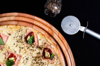 Yakın çekimde siyah bir arka plan üstüne yarım pizza