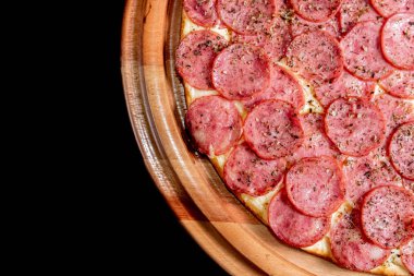 Yakın çekimde siyah bir arka plan üstüne yarım pizza