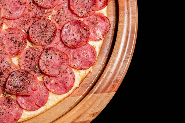 Meia pizza em cima de um fundo preto de perto — Fotografia de Stock