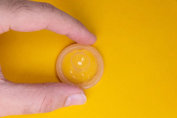 Hombre Sosteniendo Condón Látex Sobre Fondo Amarillo — Foto de Stock