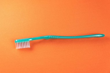 Turuncu arka planda yeşil diş fırçası