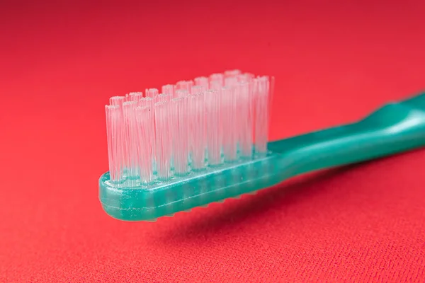 赤い背景の緑の歯ブラシ — ストック写真