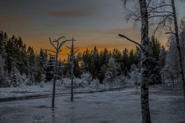 İsveç 'te donmuş bir gölün üzerinde portakal rengi gündoğumuyla buz gibi bir sabah.