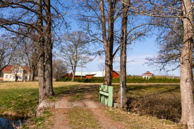 Bir bahar günü, küçük bir köprü ve İsveç kırmızısıyla kırsal bir manzara. 