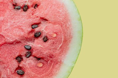 Sarı zemin üzerinde siyah tohumlar olan olgun karpuzun yarısı.