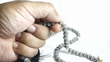 Beyaz arka plan üzerinde izole tespih tutan adam