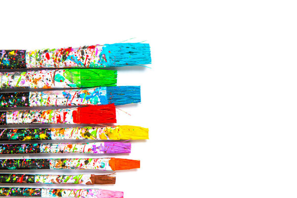 Artistic background. Artist paintbrushes with colourful paint stains isolated on white background with copy space