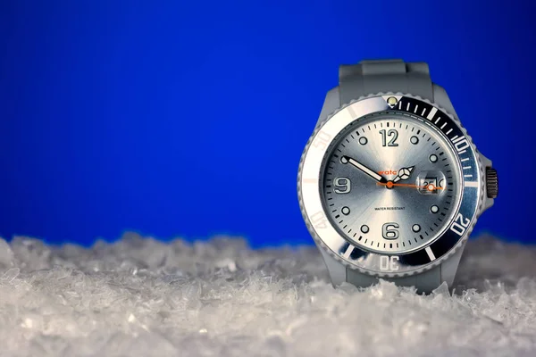 コピー スペースを持つ青い雪背景に銀の腕時計 — ストック写真