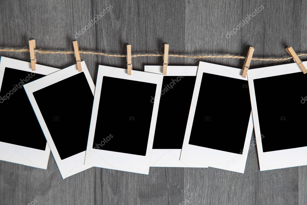 Blank vintage instant photos with empty space hanging on rope on wooden background