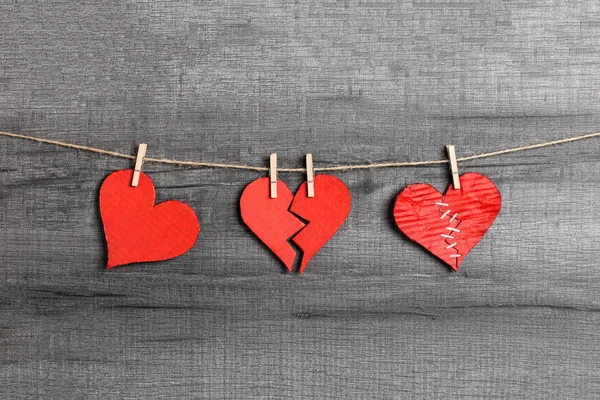 Valentine\'s Day. Red healthy / broken / stitched hearts hanging on rope. Love cycle