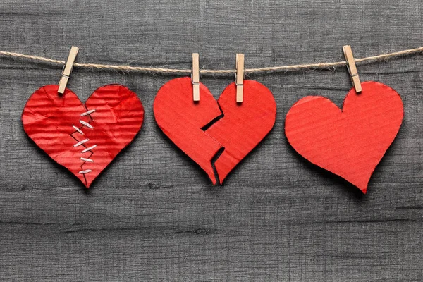 Valentine\'s Day background. Stitched / broken / healthy hearts hanging on rope. Love cycle