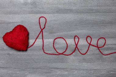Ahşap arka plan üzerinde aşk yün metin ile el yapımı örgü kırmızı yün kalp