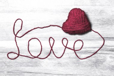 Ahşap arka plan üzerinde aşk yün metin ile el yapımı örgü kırmızı yün kalp