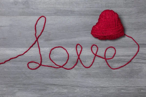 Ahşap arka plan üzerinde aşk yün metin ile el yapımı örgü kırmızı yün kalp