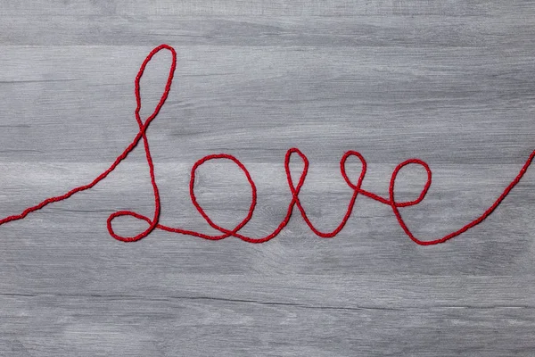 Sevgililer günü. Ahşap arka plan üzerinde kırmızı yün metin seviyorum