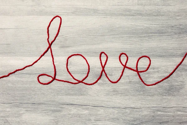 Sevgililer günü. Ahşap arka plan üzerinde kırmızı yün metin seviyorum