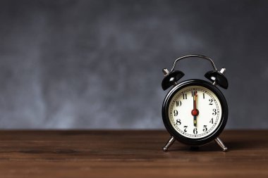 Saat 6 yönünde alarm saati 6 ' da. Koyu arka planda kopya alanı ile ahşap masada Vintage/Retro siyah analog çalar saat