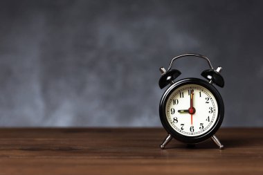 Saat 6 yönünde saati 9 ' da alarmda. Koyu arka planda kopya alanı ile ahşap masada Vintage/Retro siyah analog çalar saat