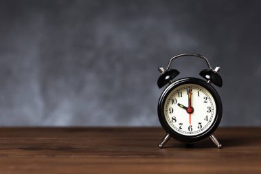 Saat 6 yönünde alarm saati 10 ' da. Koyu arka planda kopya alanı ile ahşap masada Vintage/Retro siyah analog çalar saat