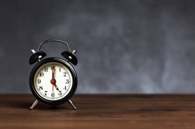 Saat 6 yönünde 5 alarmı var. Koyu arka planda kopya alanı ile ahşap masada Vintage/Retro siyah analog çalar saat