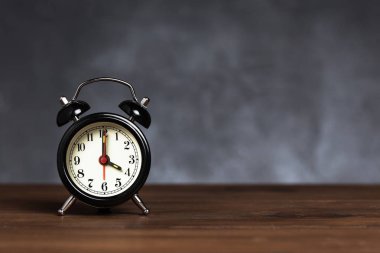 Saat 6 yönünde 4 alarmı. Koyu arka planda kopya alanı ile ahşap masada Vintage/Retro siyah analog çalar saat