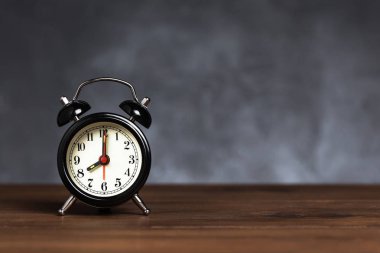 Saat 6 yönünde 8 ' de alarm var. Koyu arka planda kopya alanı ile ahşap masada Vintage/Retro siyah analog çalar saat