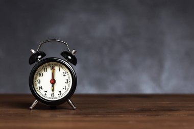 Saat 6 yönünde alarm saati 6 ' da. Koyu arka planda kopya alanı ile ahşap masada Vintage/Retro siyah analog çalar saat