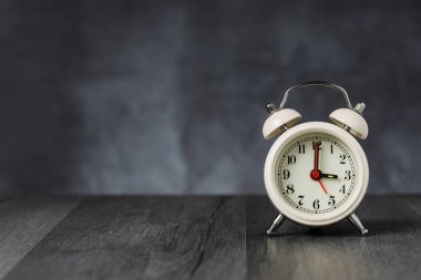 Saat 5 yönünde 3 alarmı. Koyu arka planda kopya alanı ile ahşap masada Vintage/Retro beyaz analog çalar saat