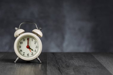 Saat 5 yönünde alarmda 4. Koyu arka planda kopya alanı ile ahşap masada Vintage/Retro beyaz analog çalar saat