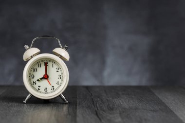 Saat 5 ' de 8 ' de alarm saati. Koyu arka planda kopya alanı ile ahşap masada Vintage/Retro beyaz analog çalar saat